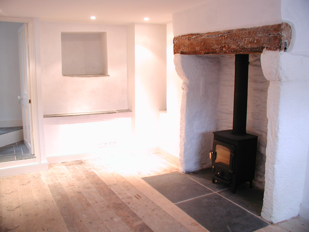 OLYMPUS DIGITAL CAMERA A room with a wooden floor and a small woodburner.