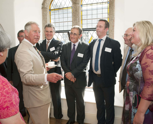 A group of people with King Charles with a large window in the background.