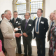 A group of people with King Charles with a large window in the background.