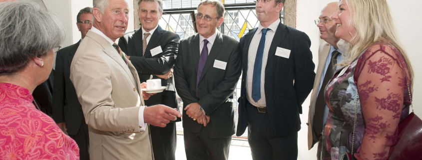 A group of people with King Charles with a large window in the background.