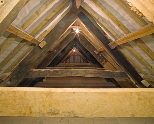 Interior of the Old Duchy Palace roof with wooden beams, dimly lit by two lights.