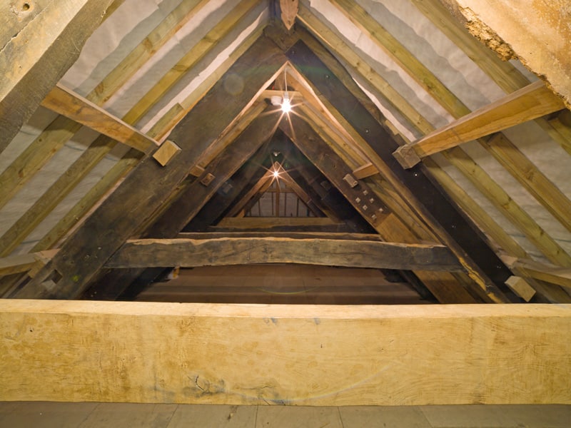 Interior of the Old Duchy Palace roof with wooden beams, dimly lit by two lights.
